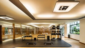 Un gimnasio moderno con equipamiento de ejercicio, ventanas amplias y suelo de madera.