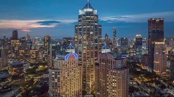 A high-rise building with a distinctive dome and illuminated signage, surrounded by other tall buildings in a cityscape.