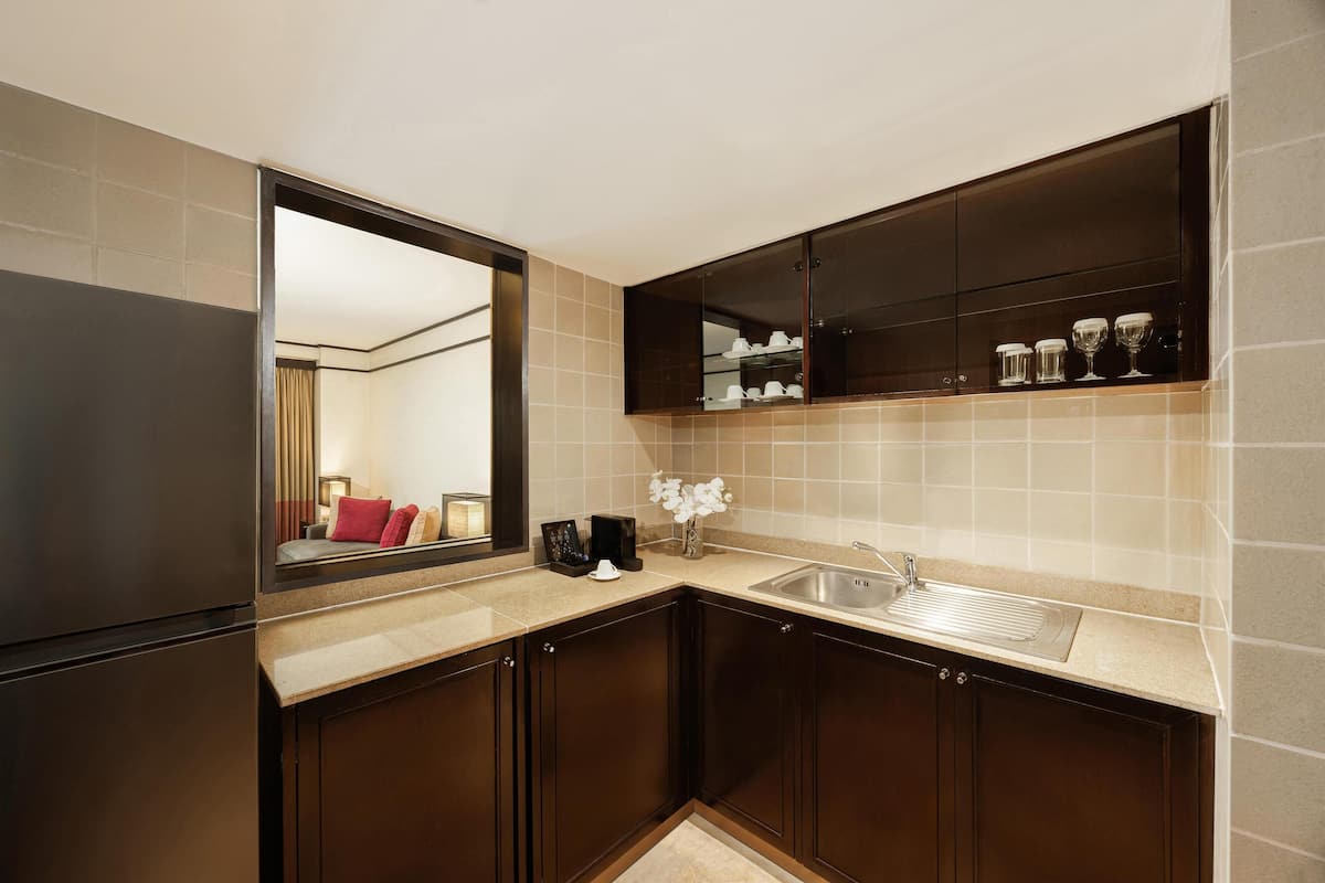 Una cocina moderna con armarios de madera oscura, un lavamanos de acero inoxidable y un espejo grande sobre la encimera.