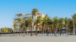 A beachfront hotel with multiple floors, palm trees, and beach chairs. - Beach Park Acqua Resort (Aquiraz)