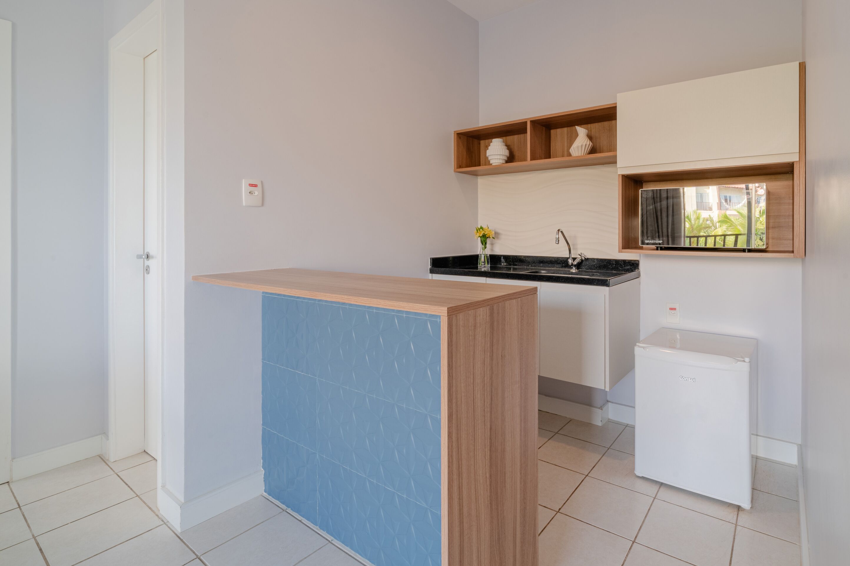 A compact kitchen with a wooden counter, a built-in microwave, and a small refrigerator.