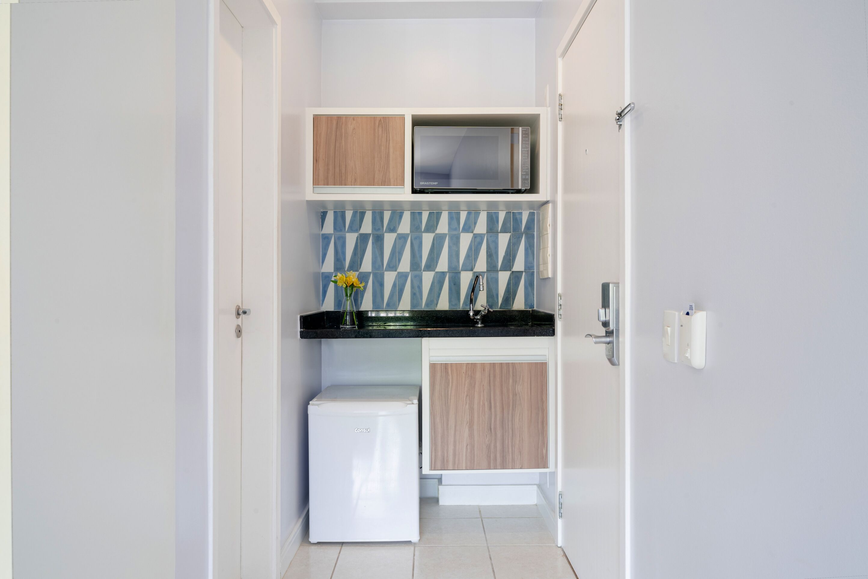 A compact kitchen with a refrigerator, microwave, and wooden cabinets.