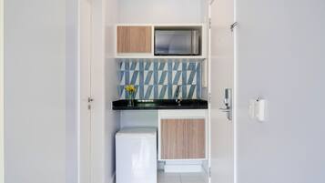 A compact kitchen with a refrigerator, microwave, and wooden cabinets.