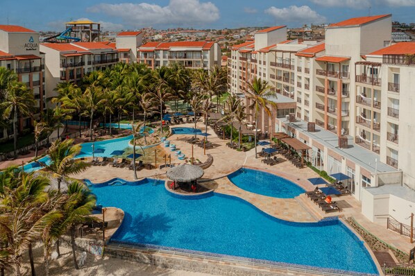 A resort with multiple swimming pools, palm trees, and a view of the surrounding town. - Beach Park Acqua Resort (Aquiraz)