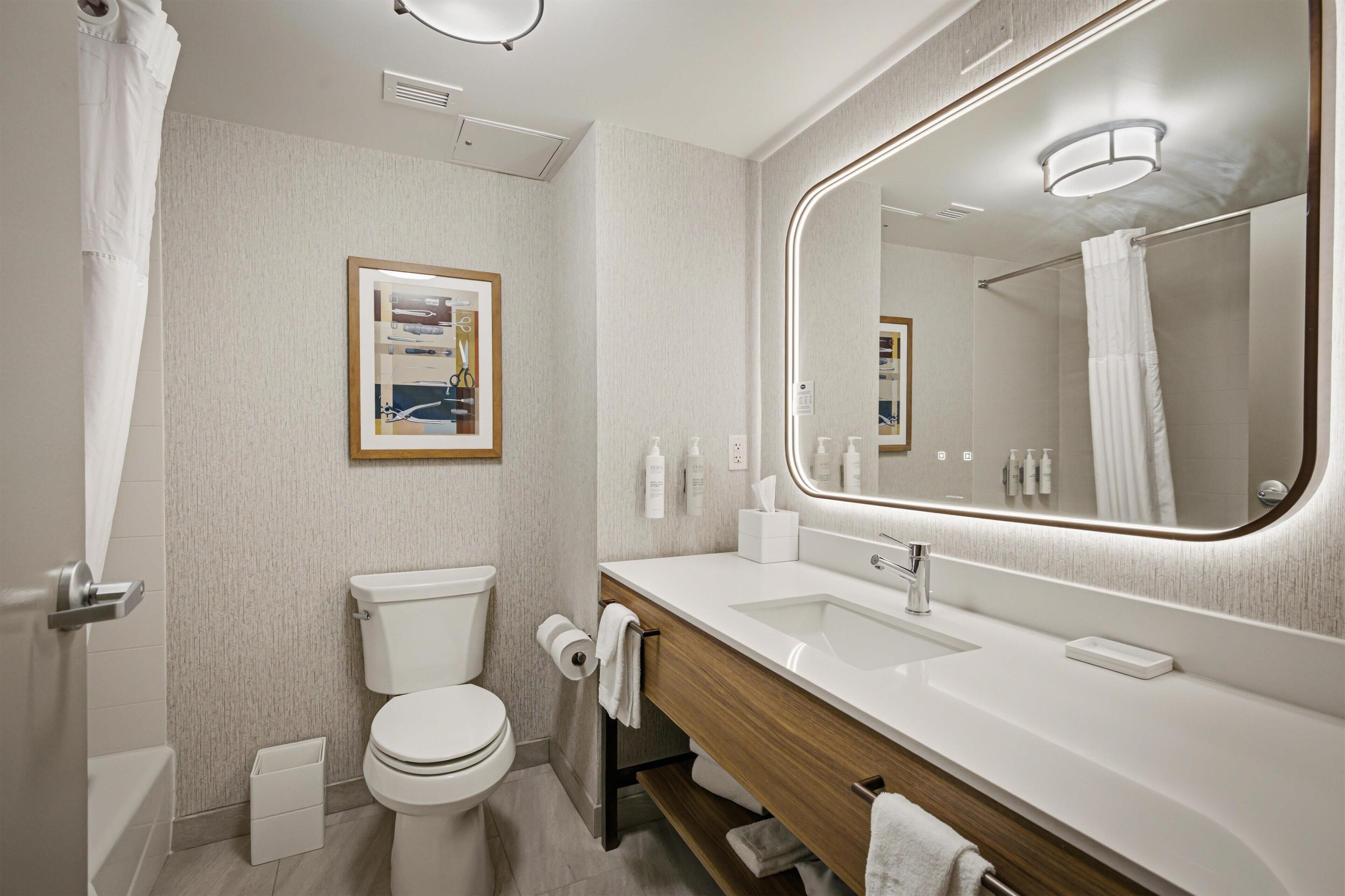 A modern bathroom with a toilet, sink, and mirror.