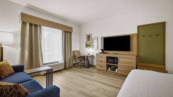 A hotel room with a bed, a sofa, a desk, a television, and a wardrobe.