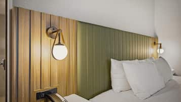 A hotel room with a wooden headboard, a bedside table with a telephone, and two wall-mounted lamps.