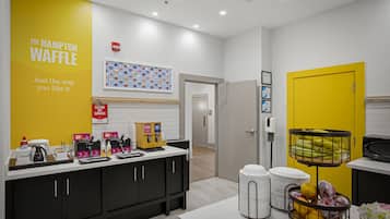 Un área de cocina moderna con pared amarilla, una estación de café y una exhibición de frutas.