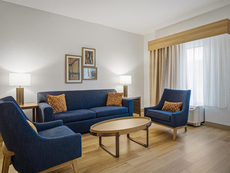 A modern living room with a blue sofa, two armchairs, a coffee table, and a TV.