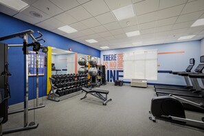 Ett gym med träningsutrustning, löpband och en vägg med motiverande citat.
