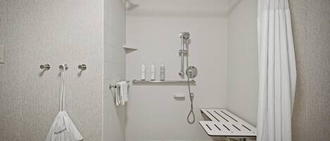 Ein kleines, modernes Badezimmer mit Dusche, Handtuchhalter und Ablagefläche für Toilettenartikel.