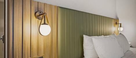 A hotel room with a wooden headboard, a bedside table with a telephone, and two wall-mounted lamps.