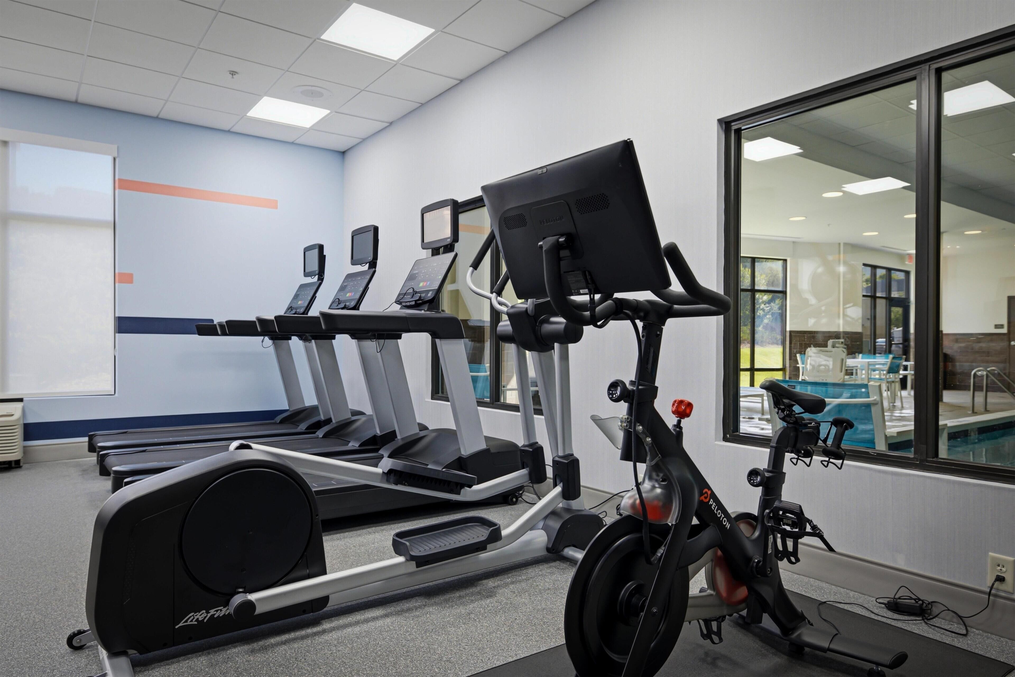 Un gimnasio con cintas de correr, una bicicleta estática y una máquina de remo.