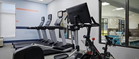 Un gimnasio con cintas de correr, una bicicleta estática y una máquina de remo.