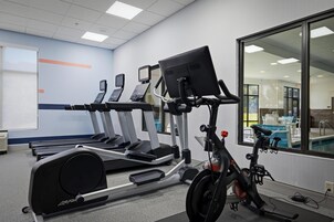 Un gimnasio con cintas de correr, una bicicleta estática y una máquina de remo.