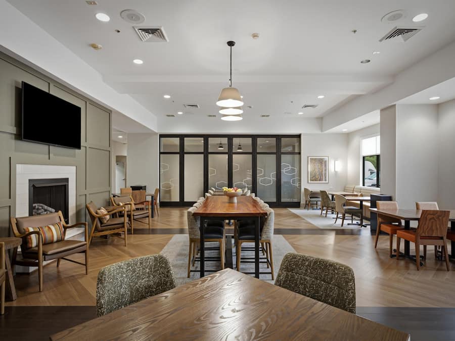 A spacious conference room with a long wooden table, multiple chairs, a fireplace, and a large window.