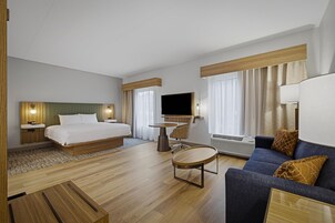A hotel room with a bed, a sofa, a TV, a desk, and a chair.
