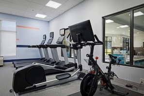 A gym with treadmills, a stationary bike, and a rowing machine.
