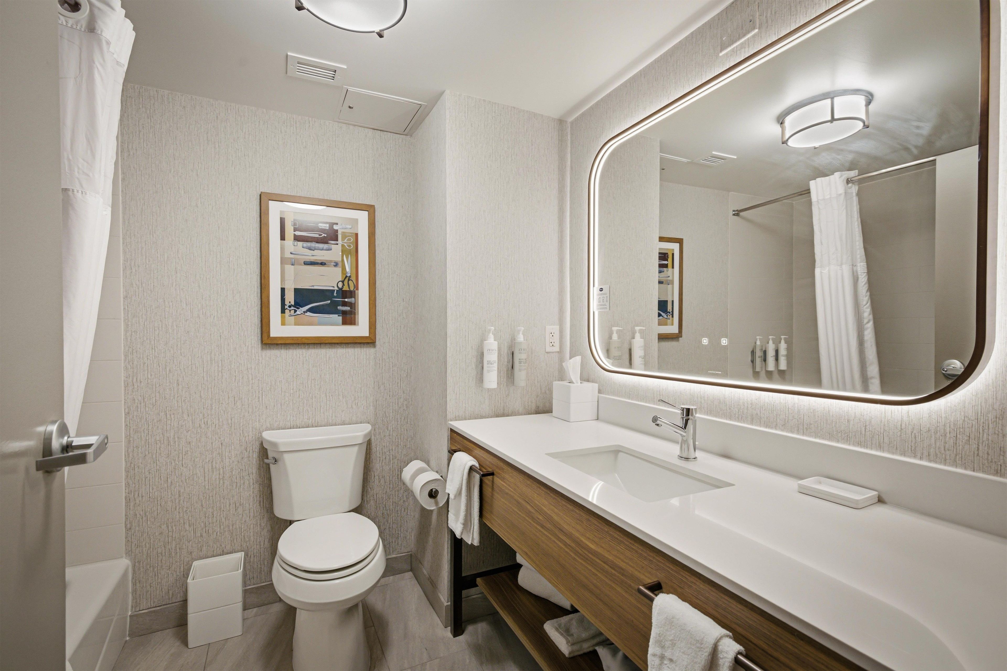 A modern bathroom with a toilet, sink, and mirror.
