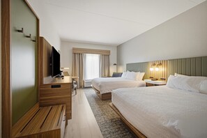 Habitación de hotel con dos camas, un escritorio, un televisor y una ventana con cortinas.
