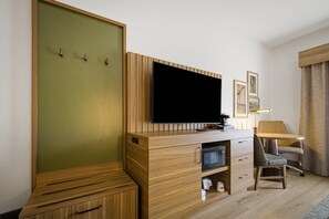 Habitación de hotel con escritorio de madera, televisor de pantalla plana, una silla, microondas y un mueble pequeño.