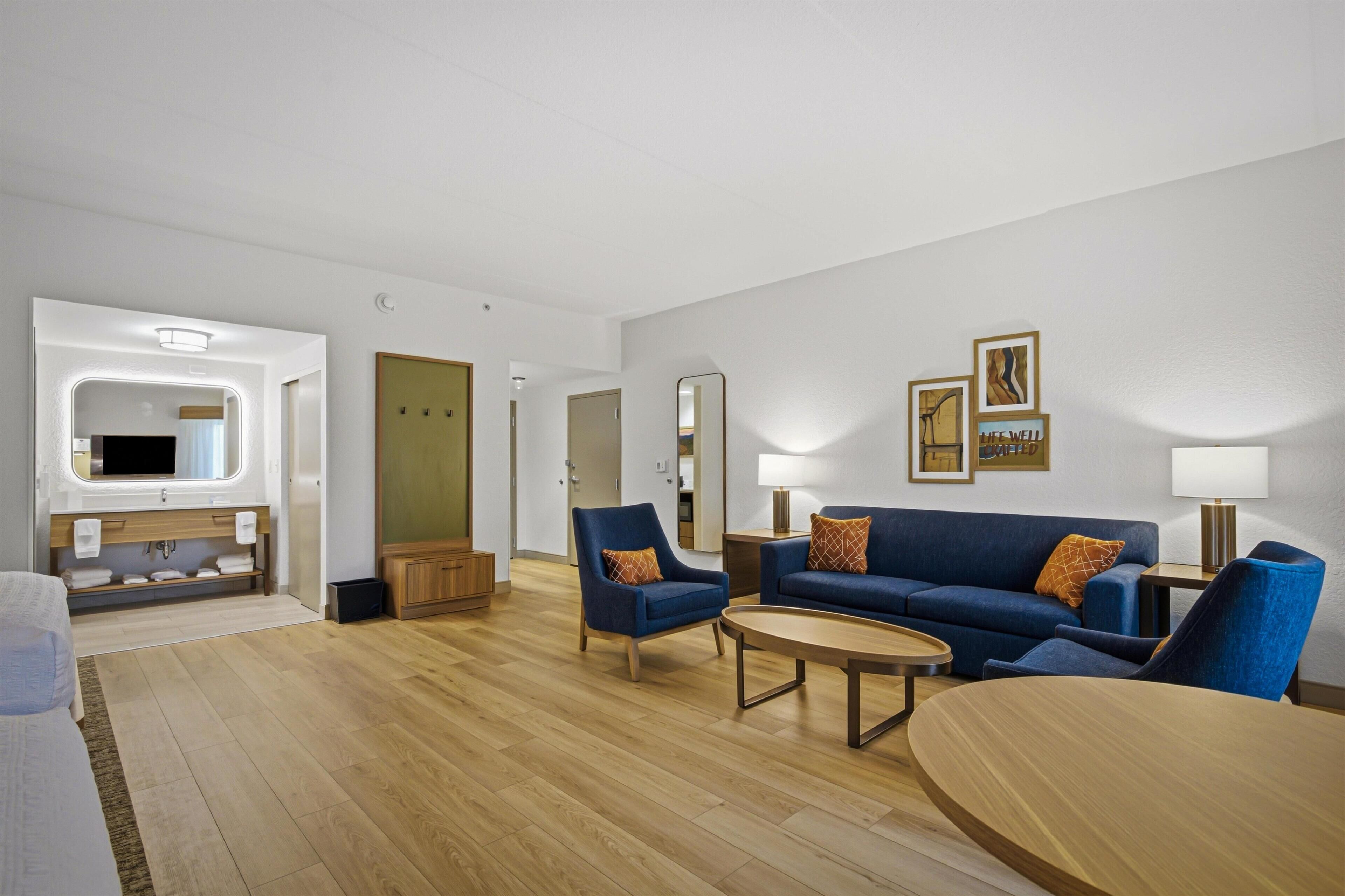 Un salón moderno con un sofá, sillones, una mesa de centro y un televisor.
