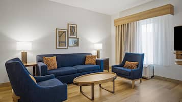 Una sala de estar moderna con un sofá azul, dos sillones, una mesita de centro y un televisor.