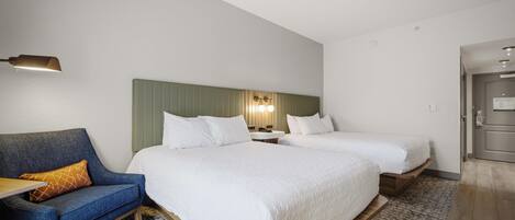 A hotel room with two beds, a sofa, a small table, and a mirror.