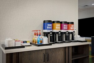 Una estación de café con cuatro dispensadores etiquetados como: tostado oscuro, tostado claro, descafeinado y agua caliente.