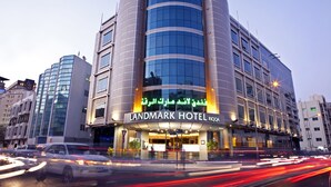 A modern hotel with a curved facade, large windows, and a prominent sign. - Landmark Hotel Riqqa (Dubai)
