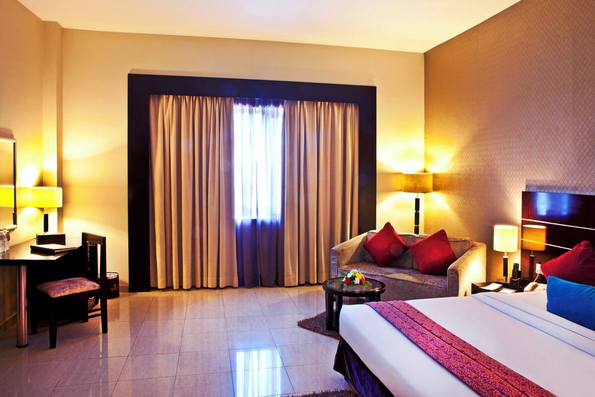 Una habitación de hotel con cama, escritorio, silla, sofá y televisor.