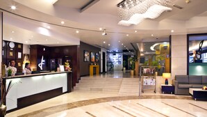 A hotel lobby with a reception desk, a chandelier, a sofa, and a coffee table. - Landmark Hotel Riqqa (Dubai)