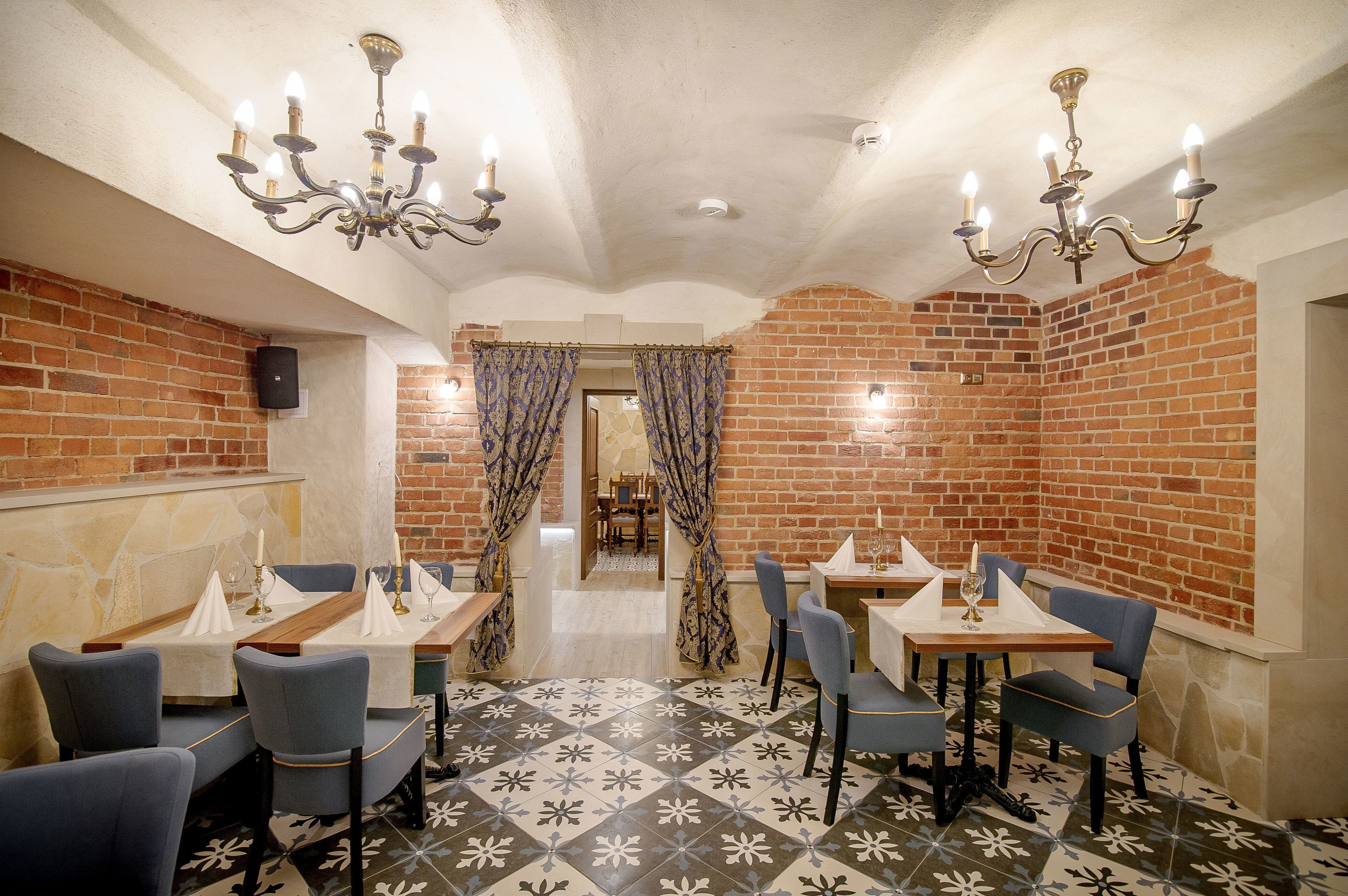A restaurant with brick walls, patterned floor tiles, and blue chairs.