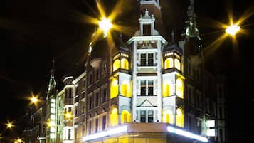 Ein historisches Gebäude mit mehreren Türmen und beleuchteten Fenstern bei Nacht.