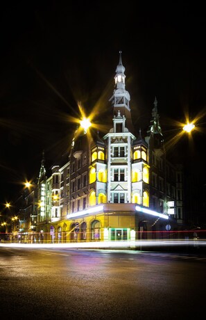 Un edificio histórico con múltiples torres y ventanas iluminadas durante la noche.
