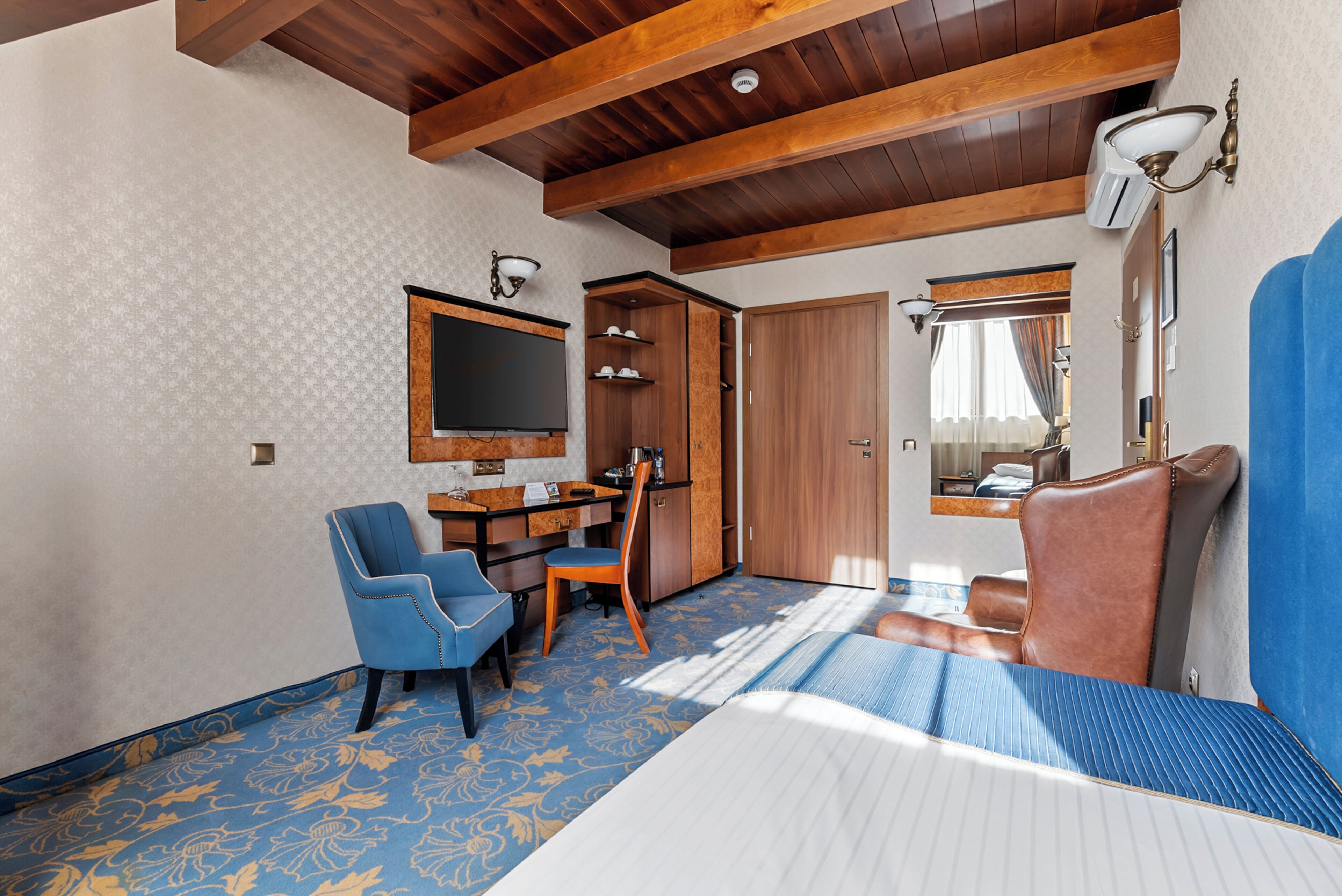 Una habitación con cama, escritorio y silla, televisor y armario.