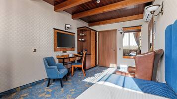 Una habitación con cama, escritorio y silla, televisor y armario.