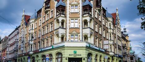 A historic building with a prominent tower, a green facade, and a sign for BNP Paribas Bank.