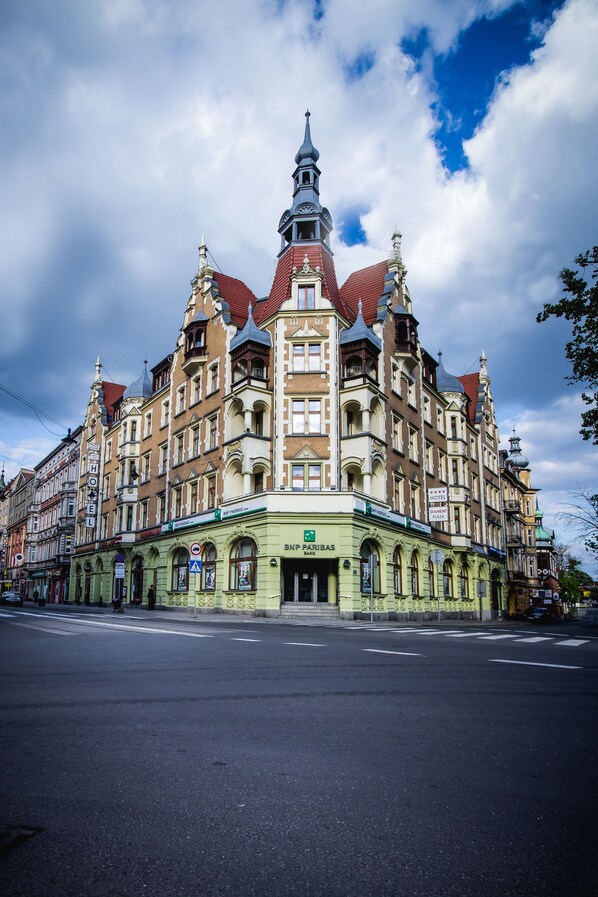 Un edificio histórico con una torre destacada, fachada verde y un cartel de BNP Paribas Bank.
