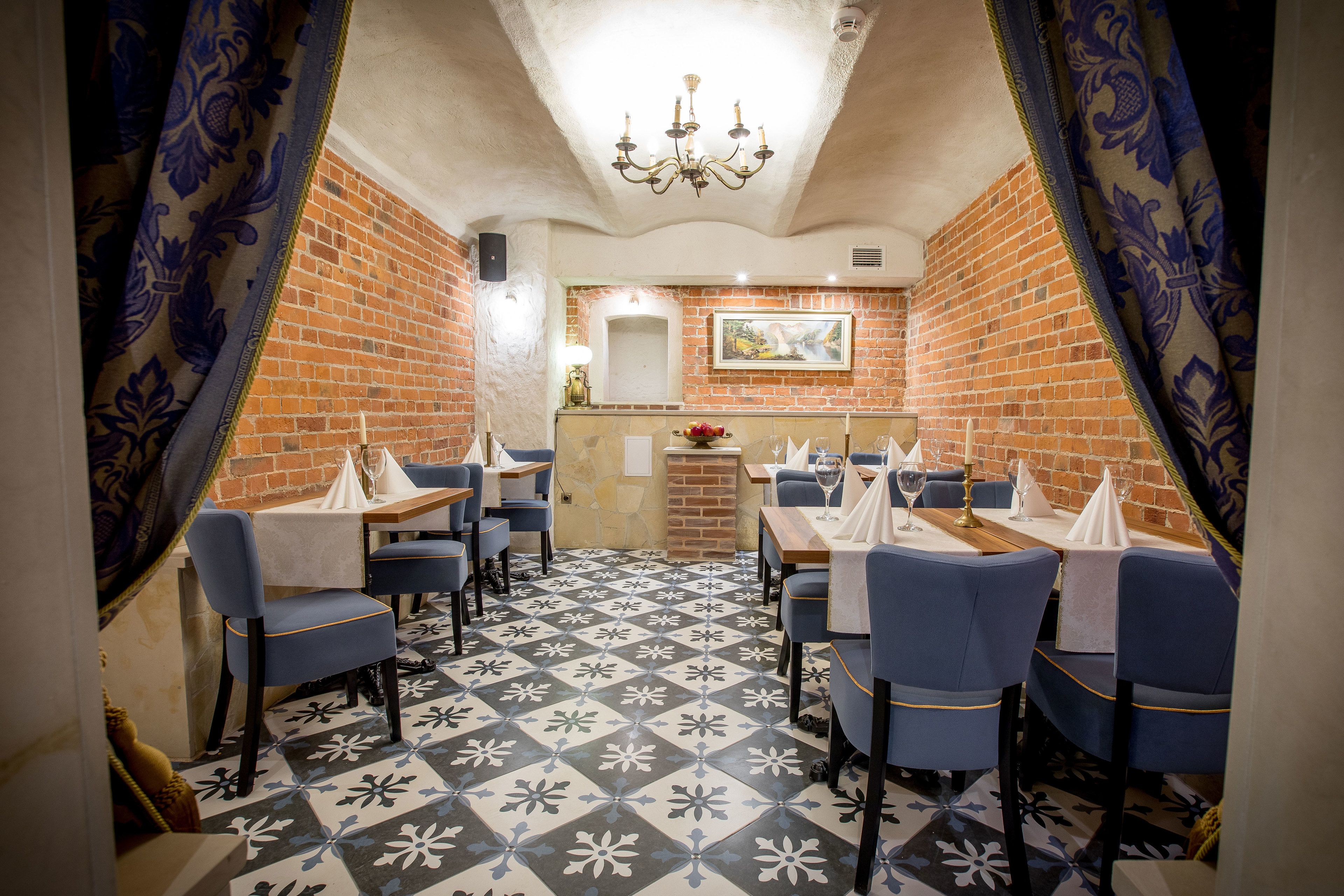 A restaurant with brick walls, blue chairs, and patterned floor tiles.