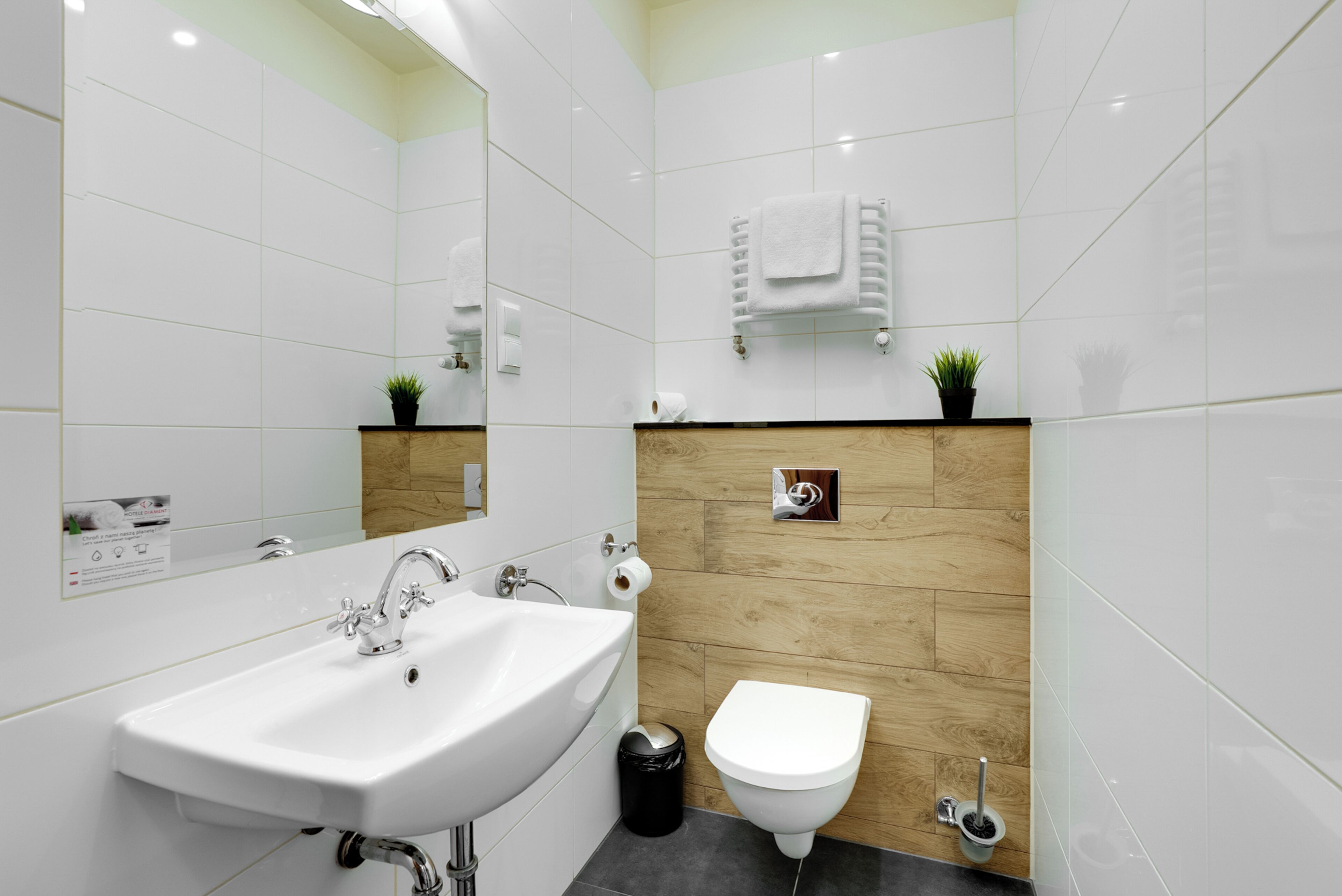 Un baño moderno con un lavabo blanco, un inodoro y un espejo.