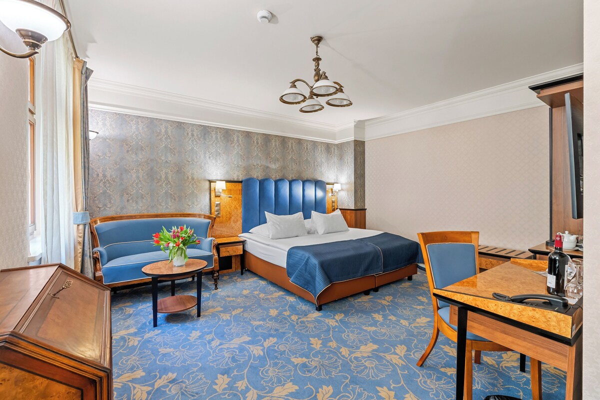 Hotellihuone, jossa on sänky, sohva, pöytä ja tuoli.