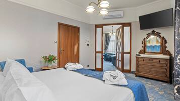 Ein Hotelzimmer mit einem großen Bett, einer Holzkommode, einem an der Wand befestigten Fernseher und einem Spiegel über der Kommode.