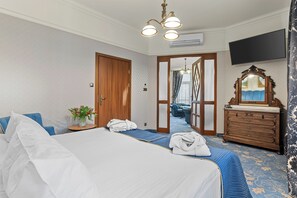 Una habitación de hotel con una cama grande, un aparador de madera, un televisor montado en la pared y un espejo sobre el aparador.