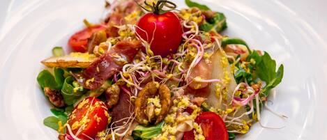 Un plato de comida con varios ingredientes como tomates, brotes y verduras.