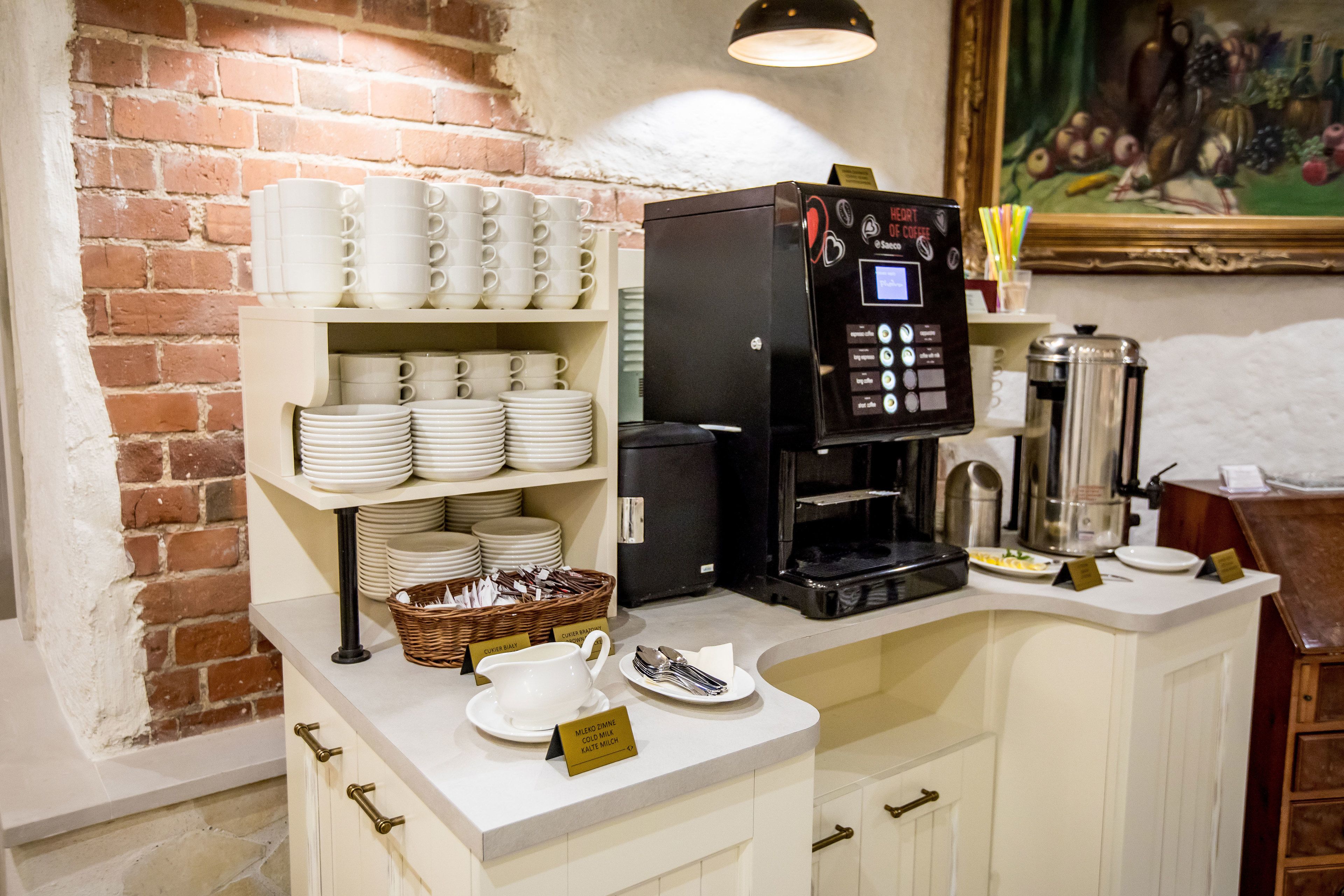 A coffee station with a coffee machine, cups, and plates.