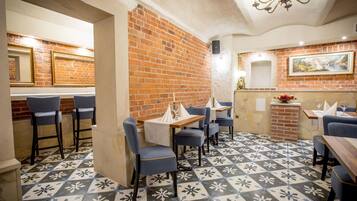 L’intérieur d’un restaurant avec des murs en briques, des chaises bleues et des carreaux de sol à motifs.