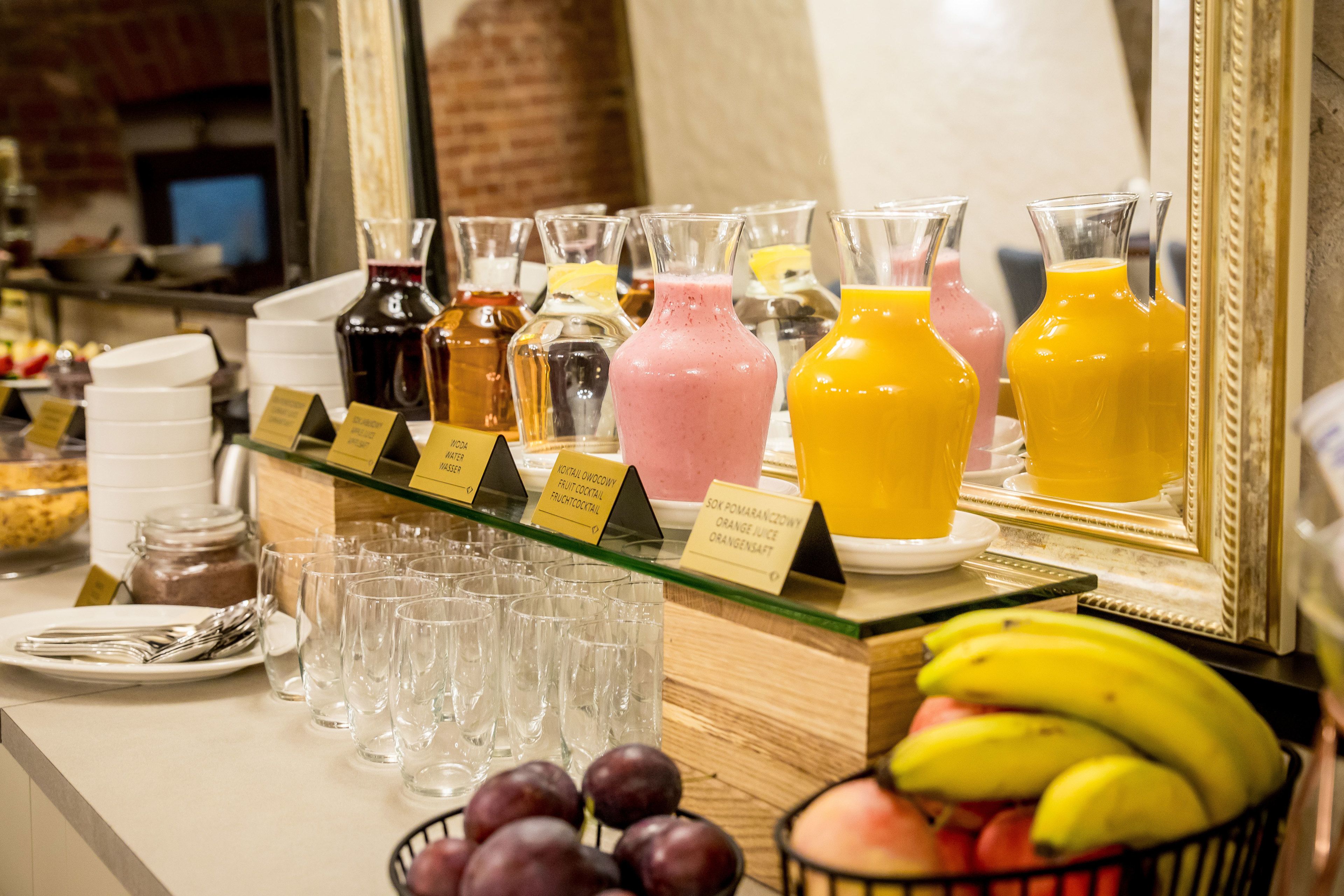 A breakfast buffet with various fruit juices, a fruit bowl, and a selection of glasses.