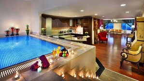 A hotel lobby with a swimming pool, a dining area, and a seating area with a view of the city. - Al Safir Hotel & Tower (Manama)