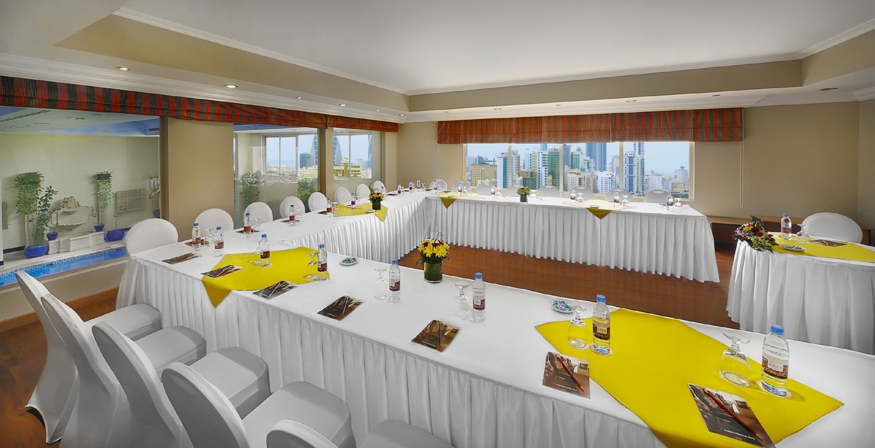 Ein Konferenzraum mit mehreren Tischen, Stühlen und Blick auf die Stadt.
